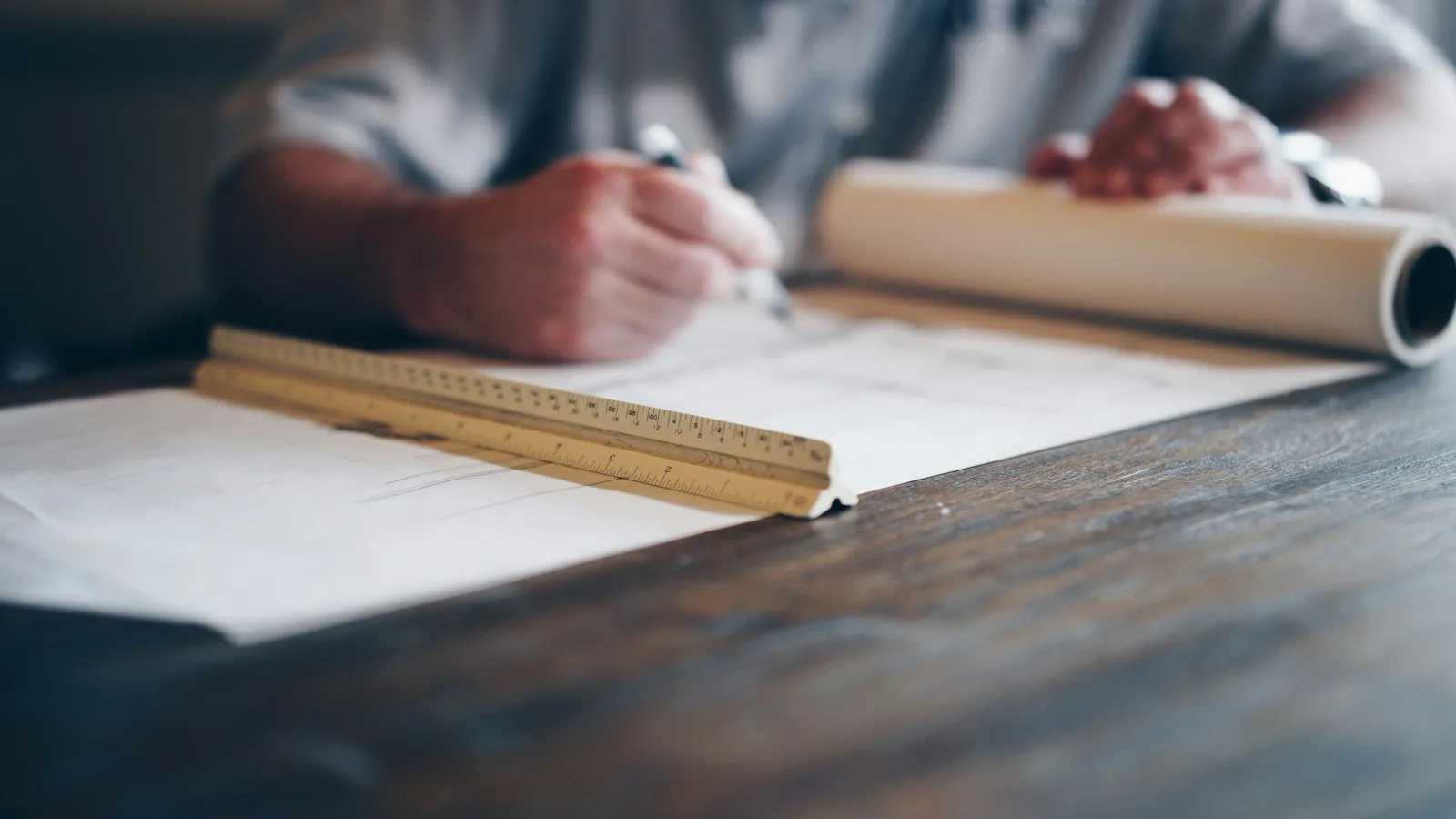 Mains qui tracent un plan sur une table, règle graduée au premier plan